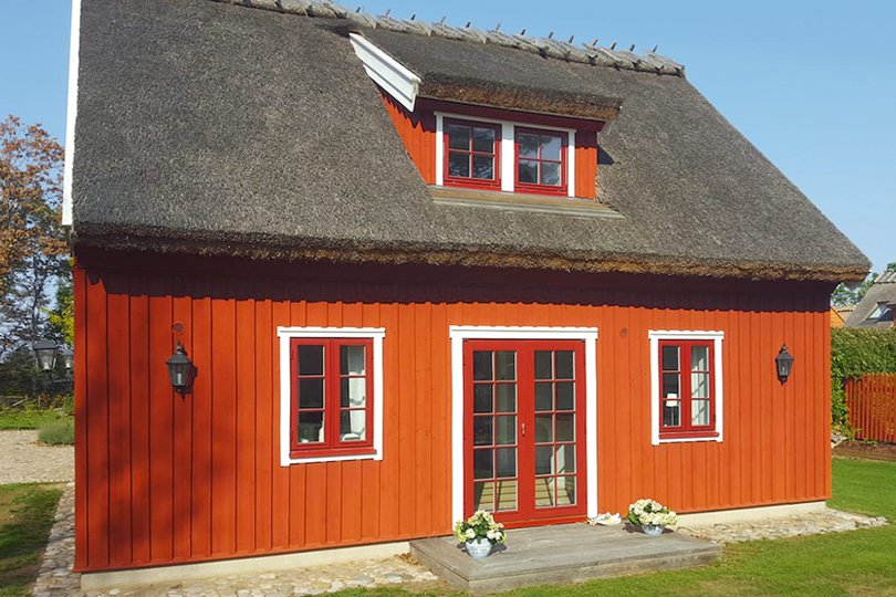 lille sommerhus med røde trævinduer med sprosser